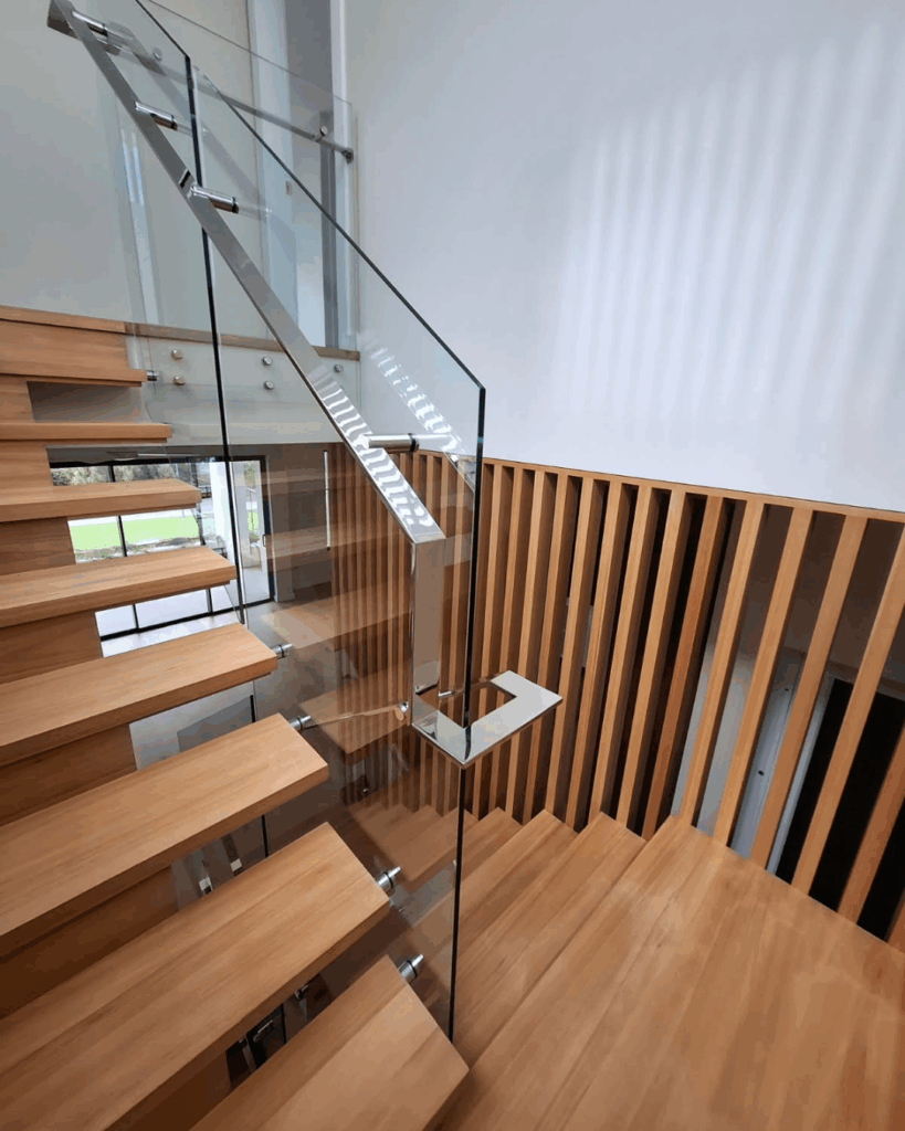 Open stairs with timber screen, frameless glass balustrade, and stainless steel handrail
