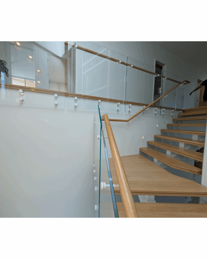 Centre mono steel stringer stair with American Oak treads, frameless glass balustrade and timber wall rail