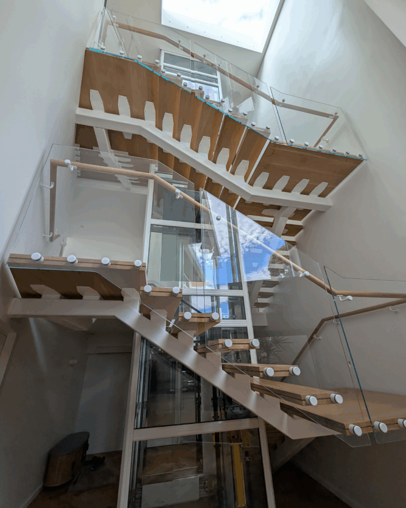 Centre mono steel stringer stair with American Oak treads, frameless glass balustrade and timber wall rail