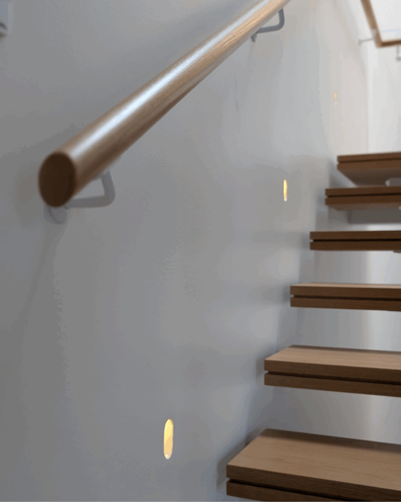 Centre mono steel stringer stair with American Oak treads, frameless glass balustrade and timber wall rail