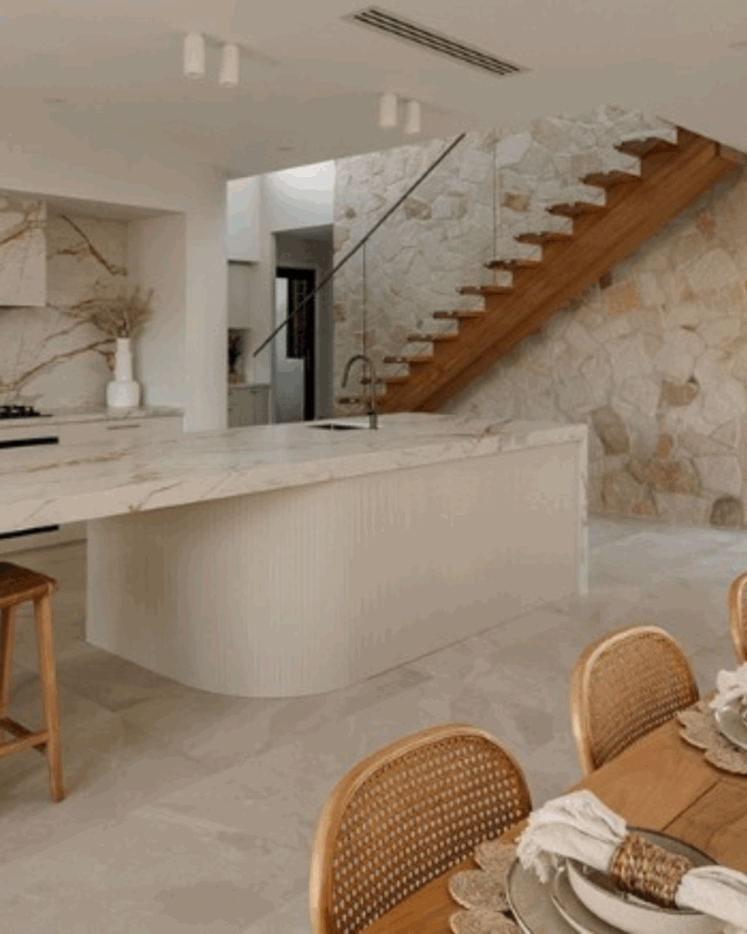 Stair with frameless glass balustrade in background with kitchen and dining table in the foreground