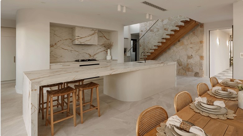 Stair with frameless glass balustrade in background with kitchen and dining table in the foreground
