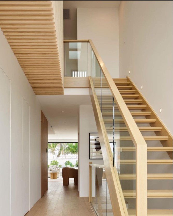 Open stair with glass balustrade in the right foreground with hallway leading to additional rooms on the left