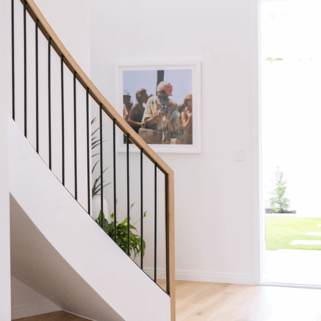 Bottom of curved staircase with powder coated balustrade in the foreground with a wall and picture in the background