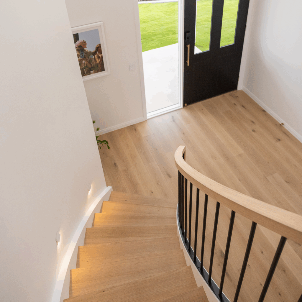 Looking down at curved timber staircase with front door in the background