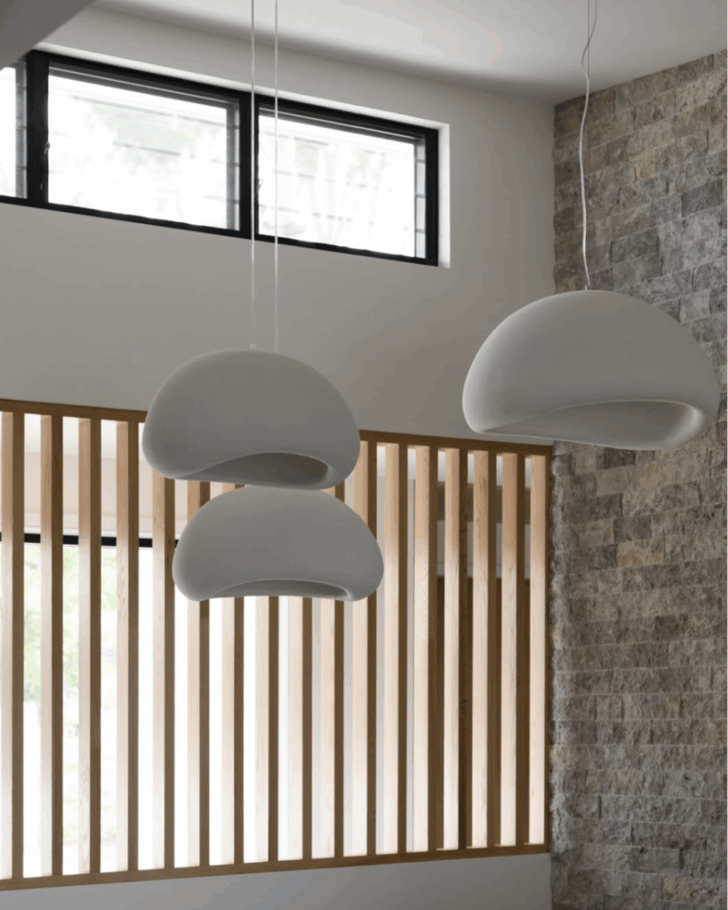 Timber screen in the background below a window and butting up to a stone wall with light fittings in the foreground