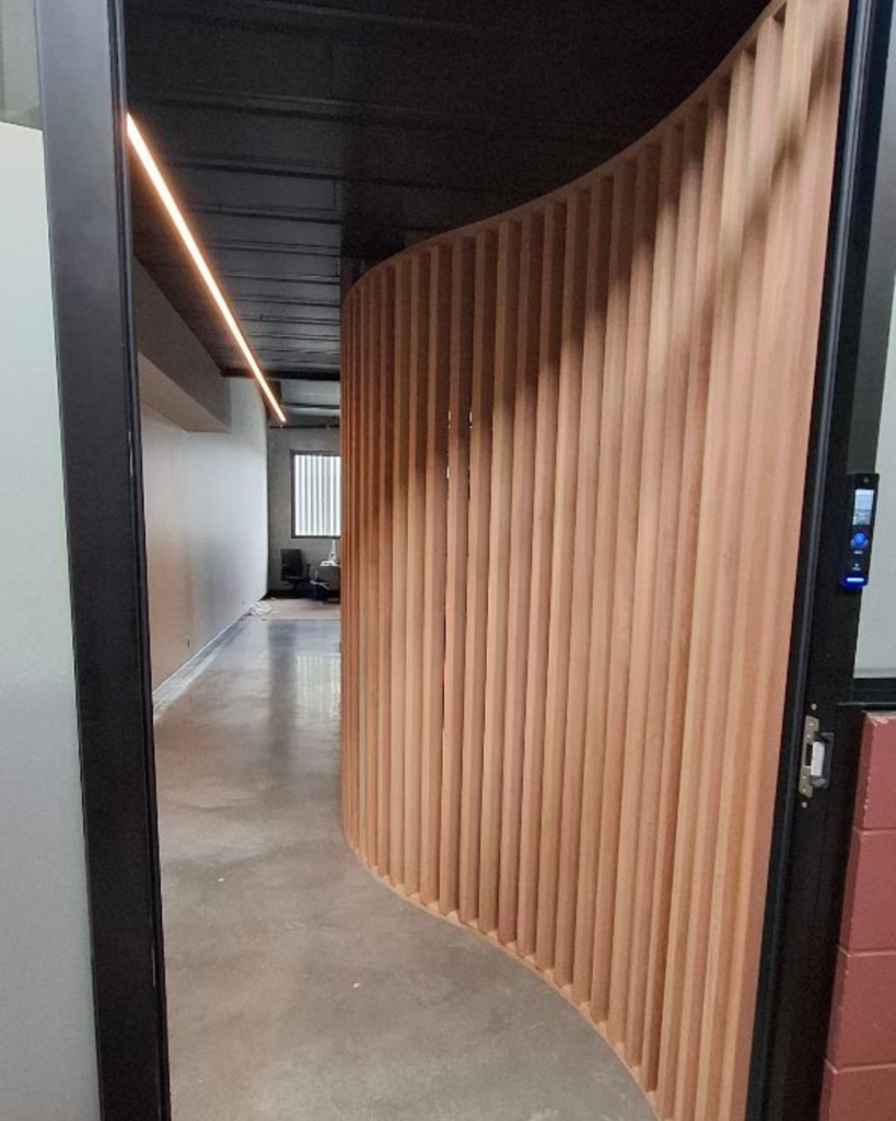 Curved timber screen made from Melunak timber in a partially finished commercial tenancy