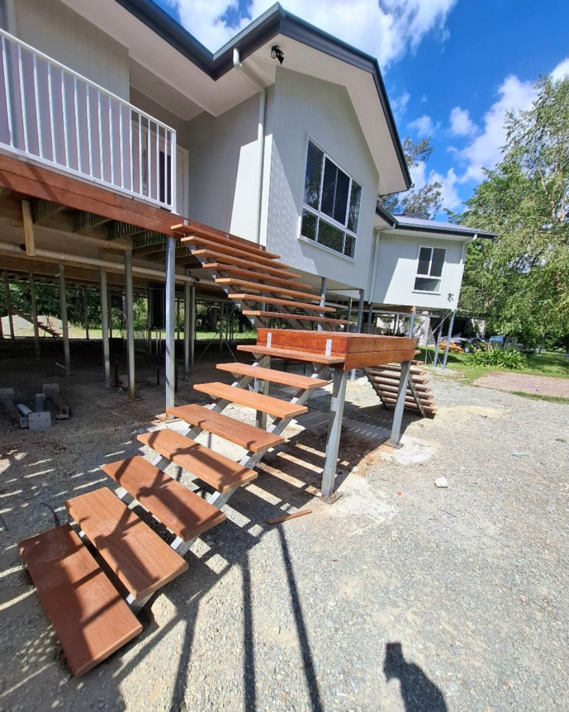 External stair with two lower flights meeting at an elevated landing platform with a single top flight. A view of the On The Way Up van is in the background