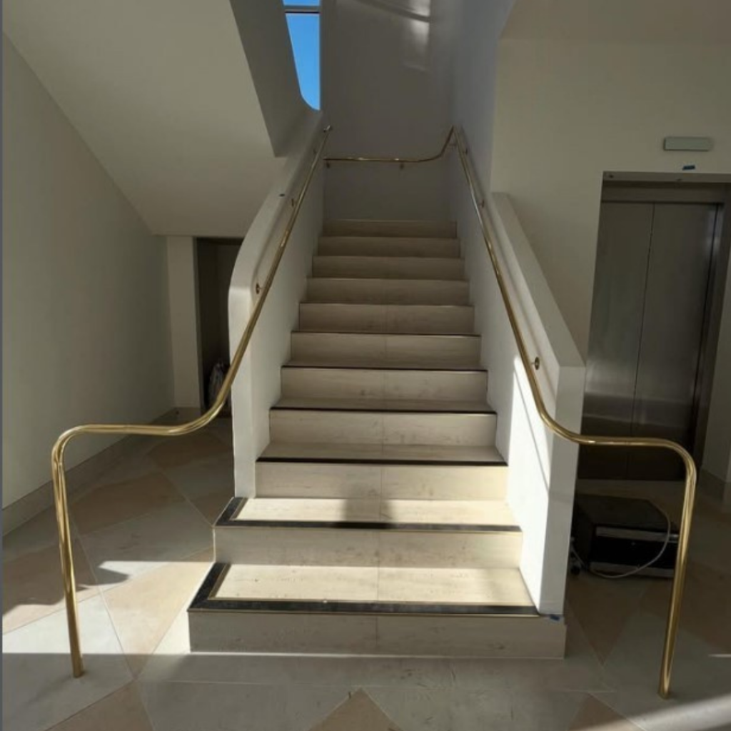 Polished brass handrail on both sides of concrete stair