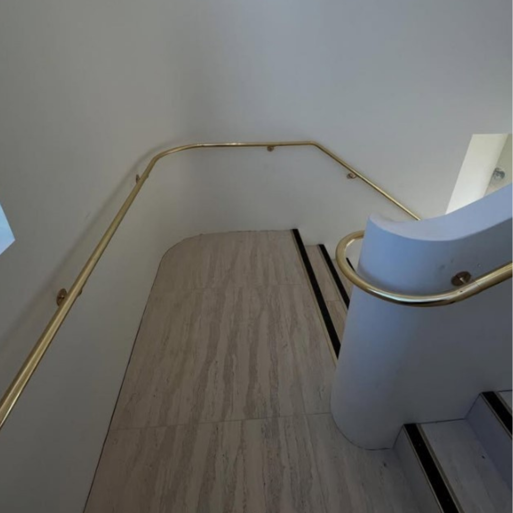 Polished brass handrail on both sides of landing