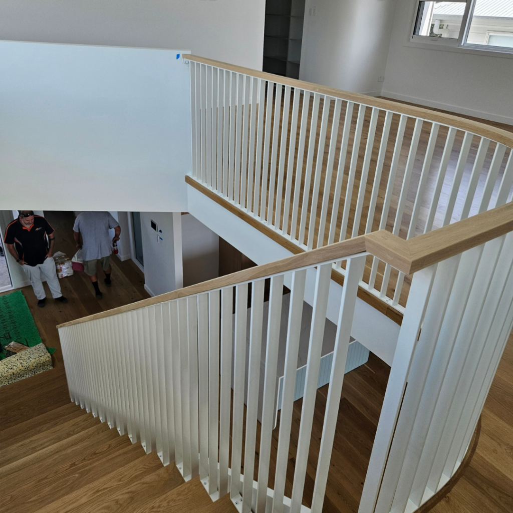 Open timber stair with modern powder coated balustrade and timber top rail.