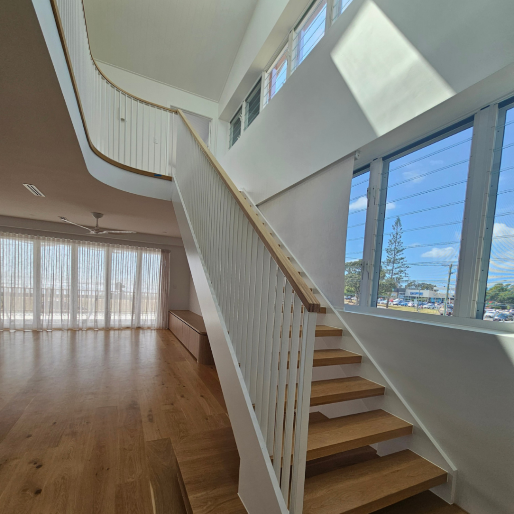 Open timber stair with modern powder coated balustrade and timber top rail.