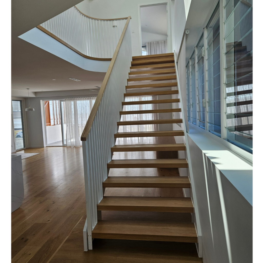 Open timber stair with modern powder coated balustrade and timber top rail.