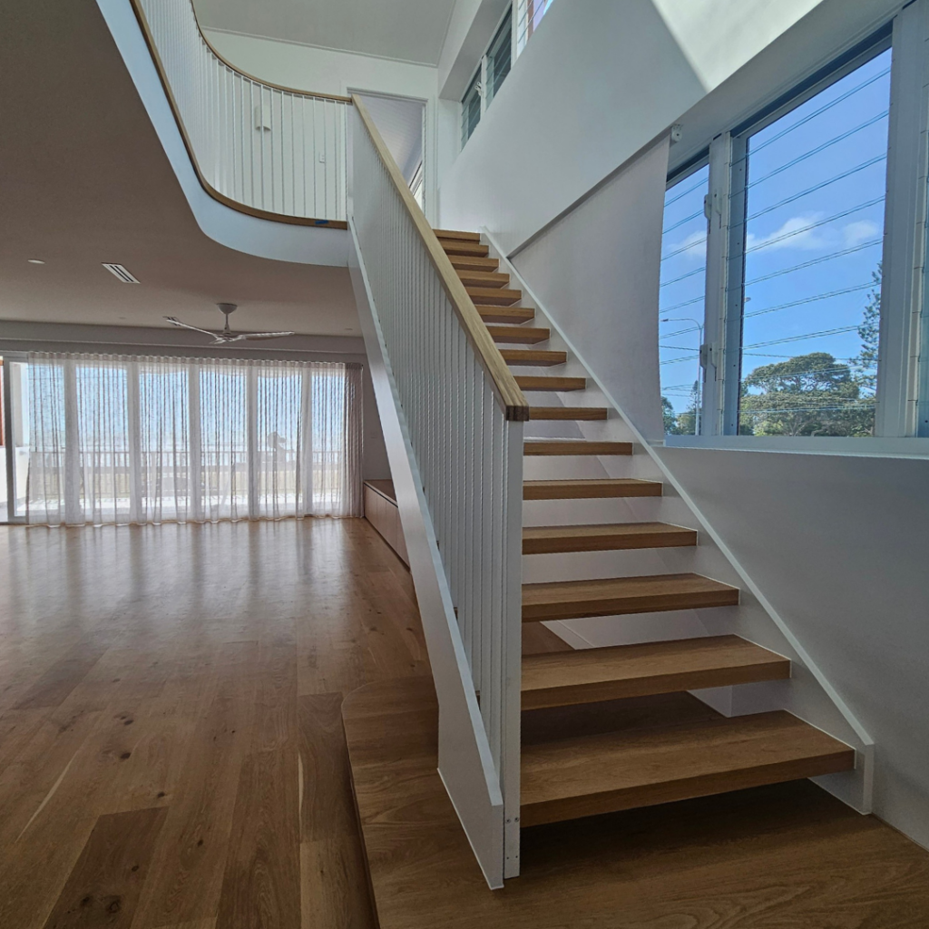 Open timber stair with modern powder coated balustrade and timber top rail.