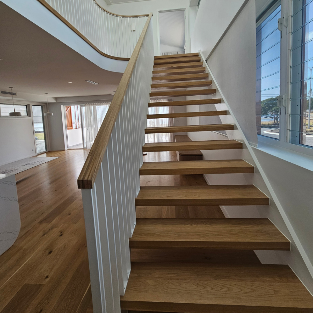 Open timber stair with modern powder coated balustrade and timber top rail.
